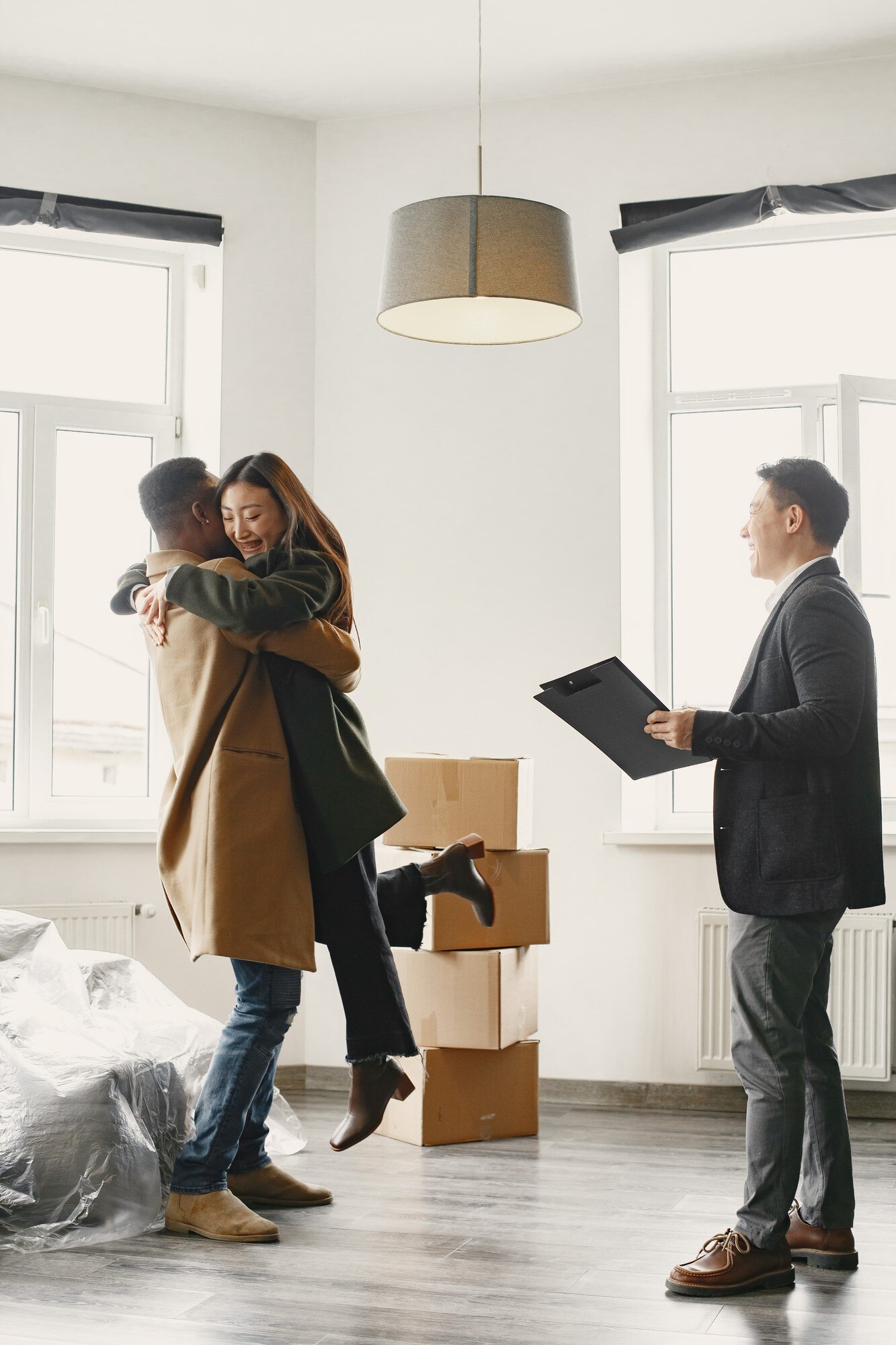 successful young couple becoming homeowners girl jumps into his boyfriend s arms hug spacious bright home with big windows 1157 47972